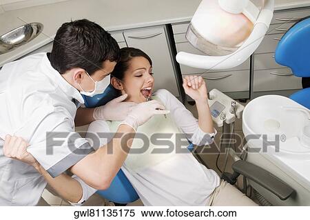 Dentist using pliers to pull out woman's teeth View Large Photo Image Stock Photography - Dentist using pliers to pull out woman's teeth. Fotosearch