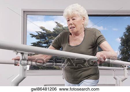 Disabled woman practicing on a walker View Large Photo Image Stock Photograph - Disabled woman practicing on a walker. Fotosearch