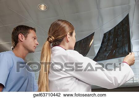 Stock Image - Doctor and a male nurse examining an MRI scan report. Fotosearch