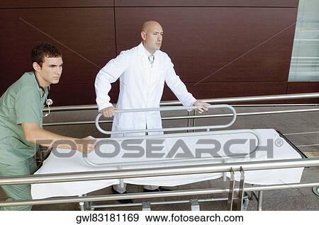 Doctor and a male nurse pushing a hospital gurney View Large Photo Image Stock Photo - Doctor and a male nurse pushing a hospital gurney. Fotosearch