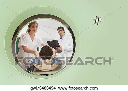Doctor and nurse preparing a patient for MRI scan View Large Photo Image Picture - Doctor and nurse preparing a patient for MRI scan. Fotosearch