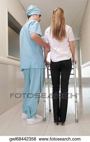 Doctor assisting a patient to walk in a hospital corridor View Large Photo Image Stock Photo - Doctor assisting a patient to walk in a hospital corridor. Fotosearch