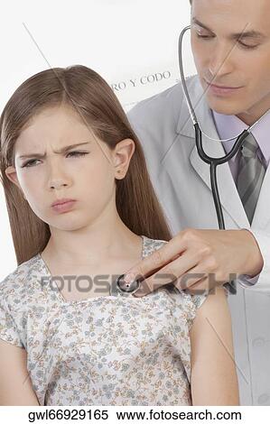 Doctor examining a girl with a stethoscope View Large Photo Image Stock Photography - Doctor examining a girl with a stethoscope. Fotosearch