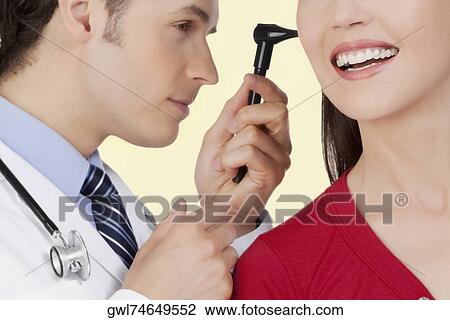 Doctor examining a woman's ear with an otoscope View Large Photo Image Stock Image - Doctor examining a woman's ear with an otoscope. Fotosearch
