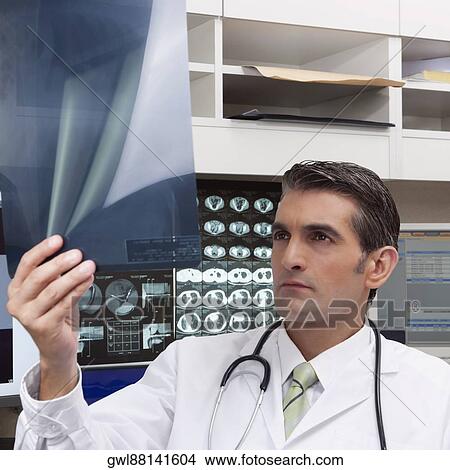 Doctor examining an x-ray report View Large Photo Image Picture - Doctor examining an x-ray report. Fotosearch