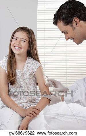 Stock Image - Doctor giving an injecting to a girl. Fotosearch