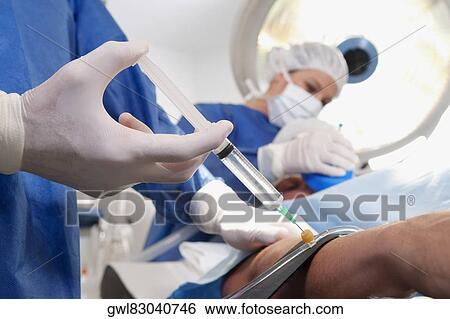 Doctor injecting patient's arm in an operating room View Large Photo Image Stock Photograph - Doctor injecting patient's arm in an operating room. Fotosearch