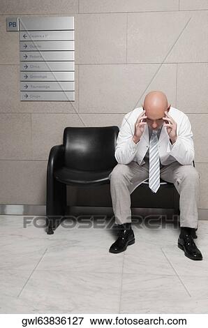 Stock Photo - Doctor sitting on a chair and looking stressed. Fotosearch