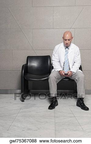 Stock Photo - Doctor text messaging on a mobile phone. Fotosearch