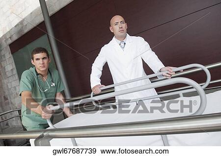 Stock Photo - Doctor with a male nurse pushing a stretcher. Fotosearch