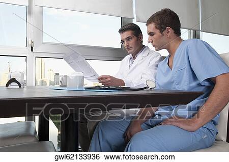 Doctors discussing a medical report in a cafeteria View Large Photo Image Stock Photograph - Doctors discussing a medical report in a cafeteria. Fotosearch