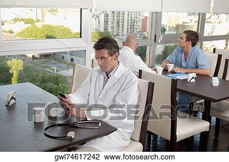 Stock Image - Doctors during coffee break a cafeteria. Fotosearch