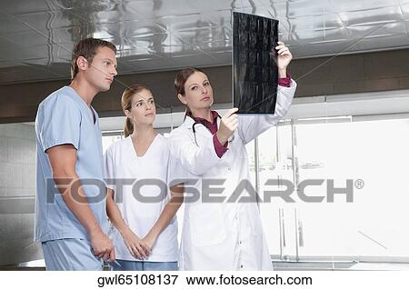 Doctors examining an X-Ray report View Large Photo Image Stock Photo - Doctors examining an X-Ray report. Fotosearch