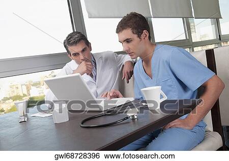 Doctors using a laptop in a cafeteria View Large Photo Image Stock Photograph - Doctors using a laptop in a cafeteria. Fotosearch
