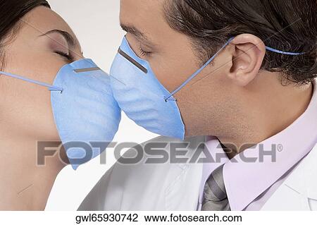 Stock Image - Doctors wearing flu masks and romancing. Fotosearch