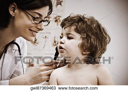 Stock Image - Female doctor examining a baby boy's ear with an otoscope. Fotosearch