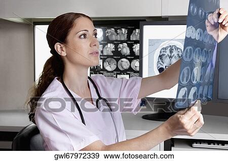 Female doctor examining an x-ray report View Large Photo Image Stock Photo - Female doctor examining an x-ray report. Fotosearch