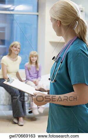 Stock Image - Female doctor holding a clipboard with patients in the background. Fotosearch