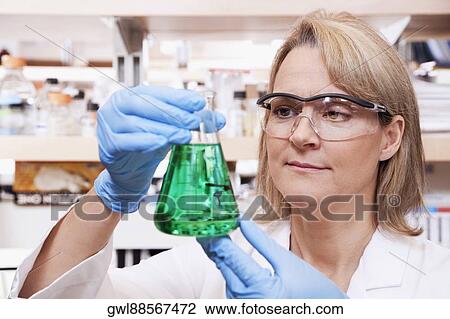 Stock Image - Female doctor holding a conical flask in a laboratory. Fotosearch