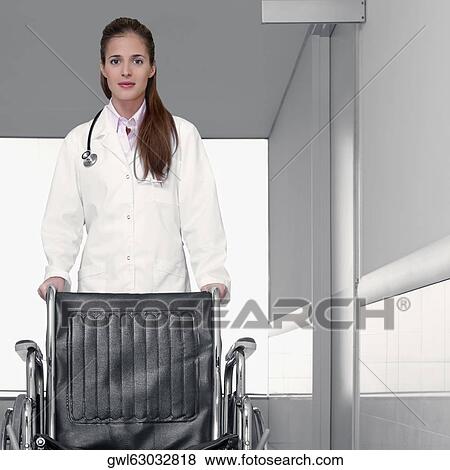 Female doctor pushing an empty wheelchair View Large Photo Image Stock Photo - Female doctor pushing an empty wheelchair. Fotosearch
