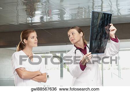 Female doctor showing MRI scan report to a nurse View Large Photo Image Stock Photograph - Female doctor showing MRI scan report to a nurse. Fotosearch