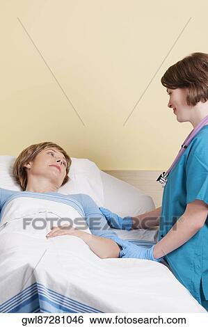 Female doctor talking to a patient lying in a hospital bed View Large Photo Image Stock Photograph - Female doctor talking to a patient lying in a hospital bed. Fotosearch