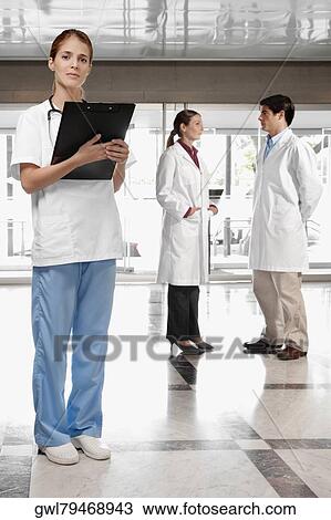 Stock Image - Female doctor with her colleagues in the background. Fotosearch