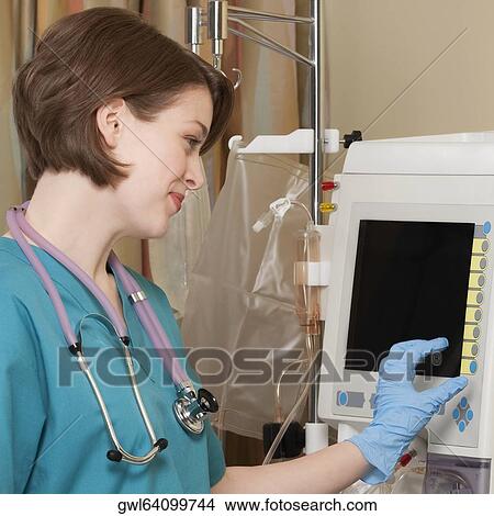 Female doctor working on a cardiac monitor View Large Photo Image Picture - Female doctor working on a cardiac monitor. Fotosearch