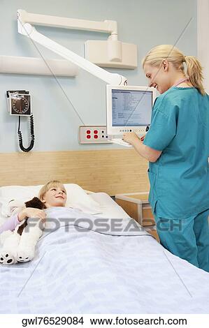 Picture - Female doctor working on a cardiac monitor. Fotosearch