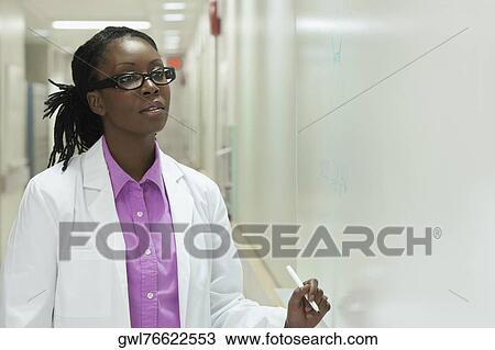 Stock Image - Female doctor writing on a whiteboard in a hospital. Fotosearch