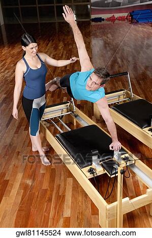 Female instructor assisting a man in a gym View Large Photo Image Picture - Female instructor assisting a man in a gym. Fotosearch