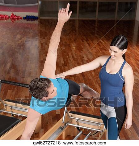 Female instructor assisting a man in a gym View Large Photo Image Stock Photo - Female instructor assisting a man in a gym. Fotosearch