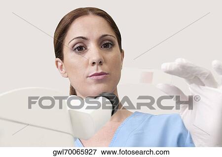 Stock Photo - Female lab technician analyzing a sample in a laboratory. Fotosearch