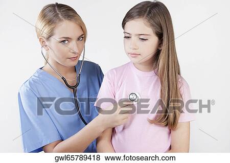 Female nurse examining a girl with a stethoscope View Large Photo Image Stock Photo - Female nurse examining a girl with a stethoscope. Fotosearch
