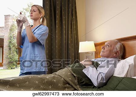 Female nurse holding a syringe and standing near a patient View Large Photo Image Stock Image - Female nurse holding a syringe and standing near a patient. Fotosearch