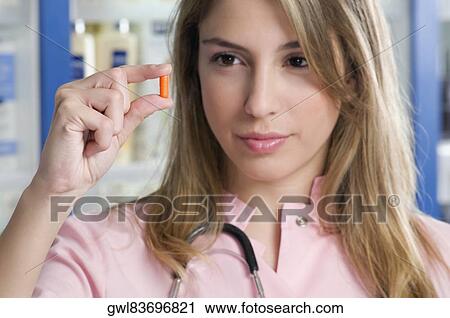 Female pharmacist holding a capsule and thinking View Large Photo Image Stock Image - Female pharmacist holding a capsule and thinking. Fotosearch