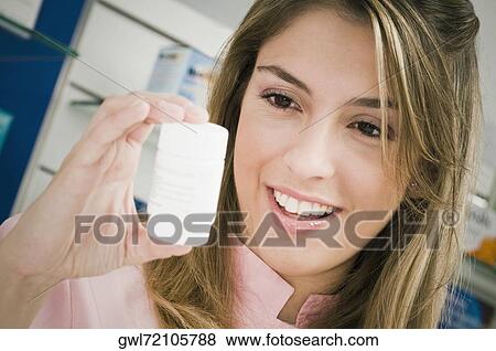 Stock Photo - Female pharmacist holding a medicine bottle. Fotosearch