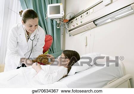 Girl on a hospital bed being examined by a female doctor View Large Photo Image Stock Photo - Girl on a hospital bed being examined by a female doctor. Fotosearch