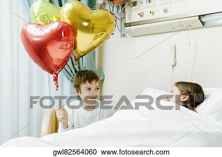 Girl on a hospital bed with her brother holding balloons View Large Photo Image Stock Image - Girl on a hospital bed with her brother holding balloons. Fotosearch