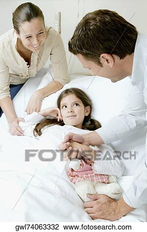 Stock Image - Girl on a hospital bed with her parents beside her. Fotosearch