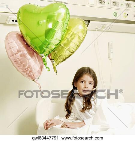 Stock Image - Girl with balloons on a hospital bed. Fotosearch