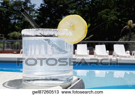 Stock Image - Glass of lemonade at the poolside. Fotosearch