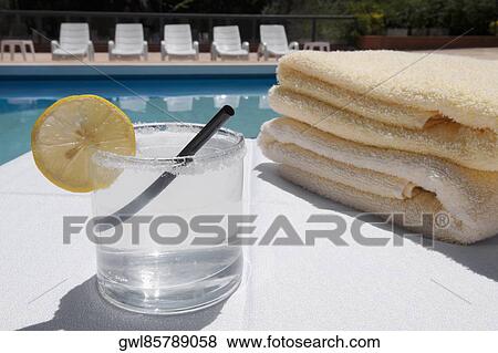 Glass of lemonade with towels at the poolside View Large Photo Image Stock Photo - Glass of lemonade with towels at the poolside. Fotosearch