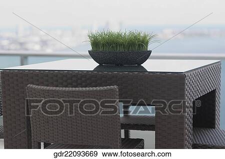Stock Photo - Grass pot on table in the balcony of a house. Fotosearch