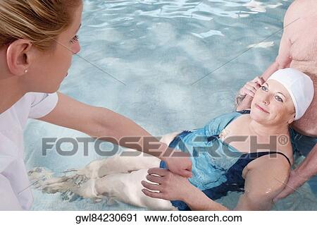 Health worker and a man assisting a woman in a swimming pool View Large Photo Image Stock Image - Health worker and a man assisting a woman in a swimming pool. Fotosearch