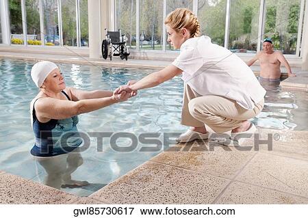 Health worker assisting a woman pulling out from a swimming pool View Large Photo Image Stock Photo - Health worker assisting a woman pulling out from a swimming pool. Fotosearch