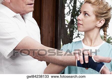 Stock Image - Health worker putting on a wrist brace to a disabled man. Fotosearch