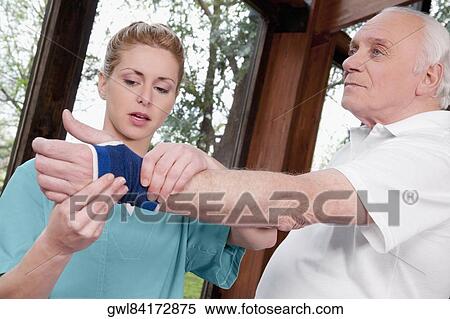 Stock Photography - Health worker putting on a wrist brace to a disabled man. Fotosearch