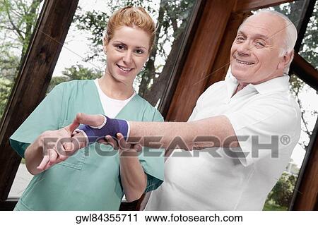 Health worker putting on wrist brace to a man View Large Photo Image Stock Image - Health worker putting on wrist brace to a man. Fotosearch