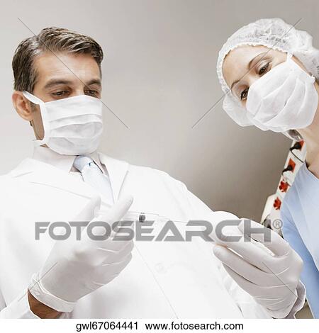 Stock Image - Lab technician injecting into an egg with her colleague standing beside him. Fotosearch